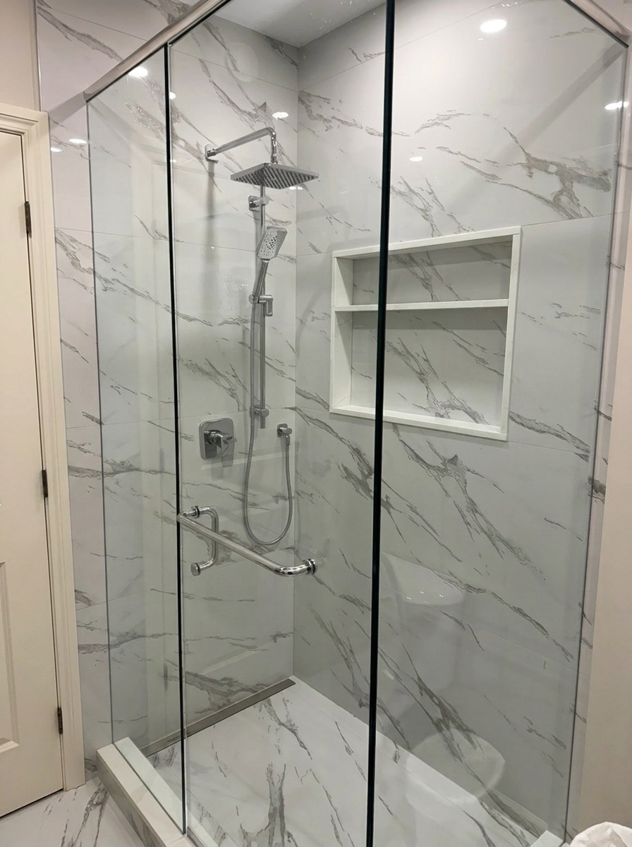 Glass shower with marble-look tile, rain head, and built-in niche