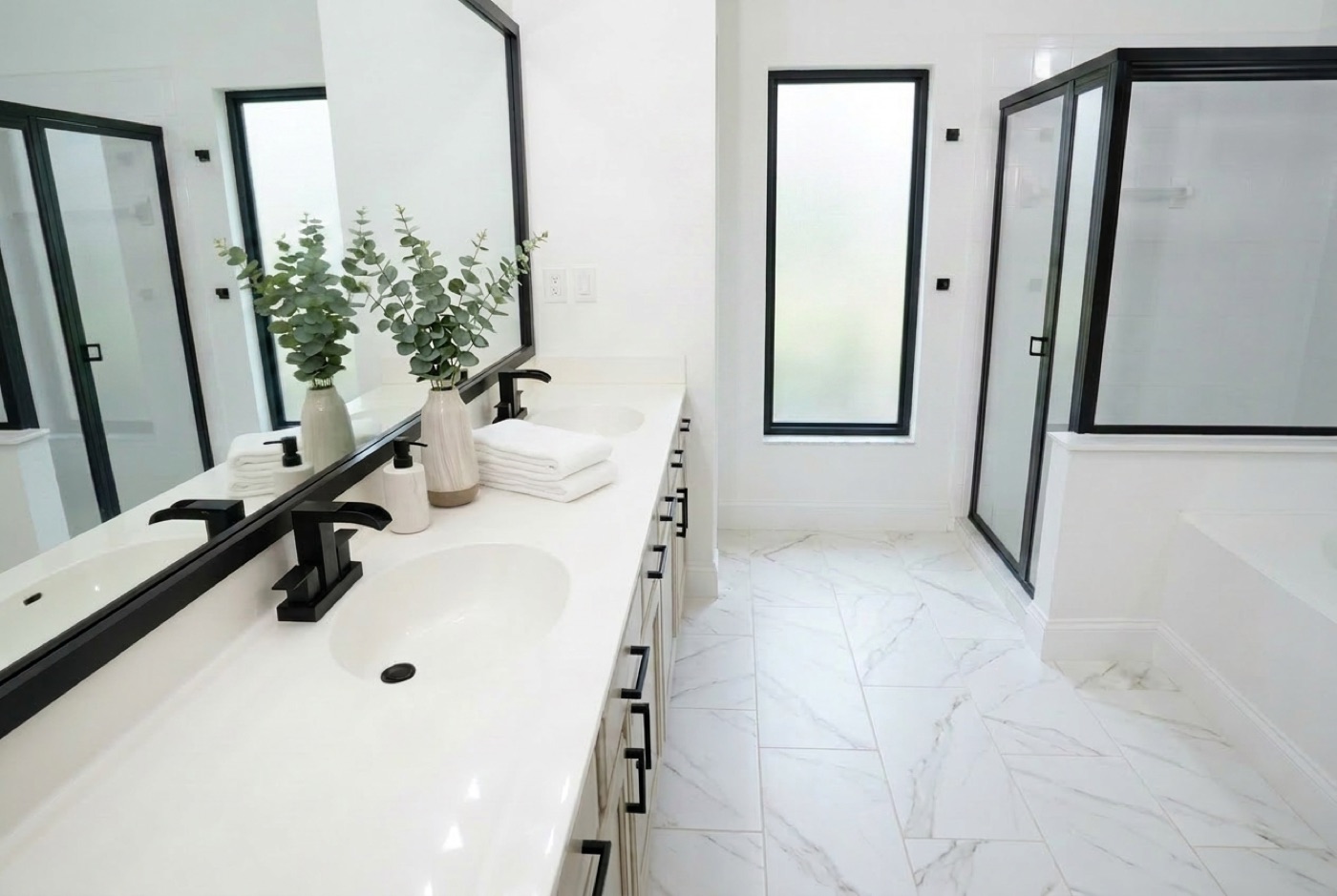 Modern bathroom with double vanity, matte black fixtures, and glass shower