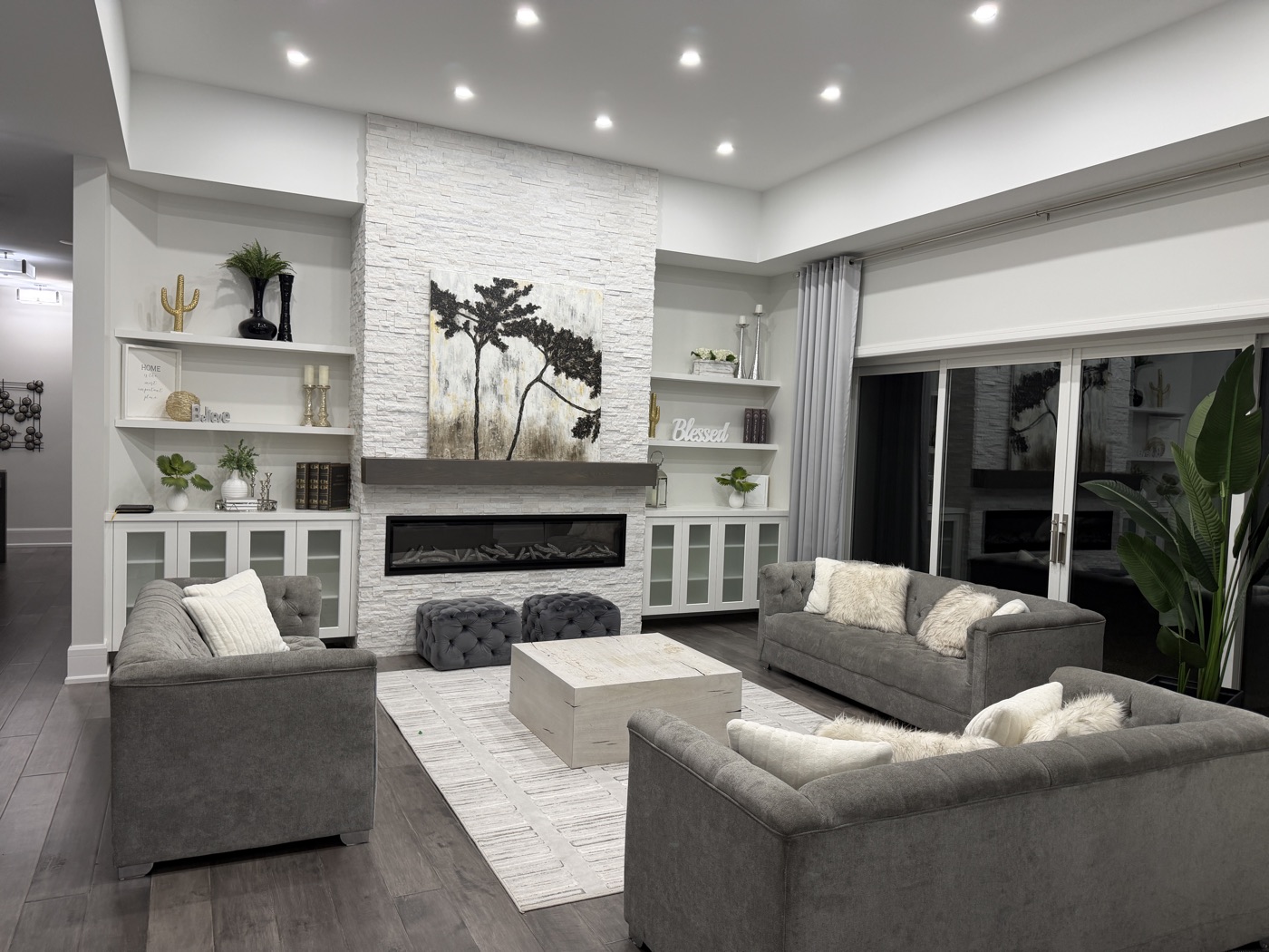 Open-concept living room with stone fireplace and custom built-ins